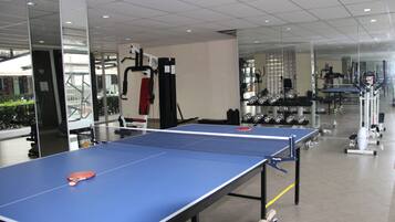 A ping pong table in a gym with exercise equipment in the background.