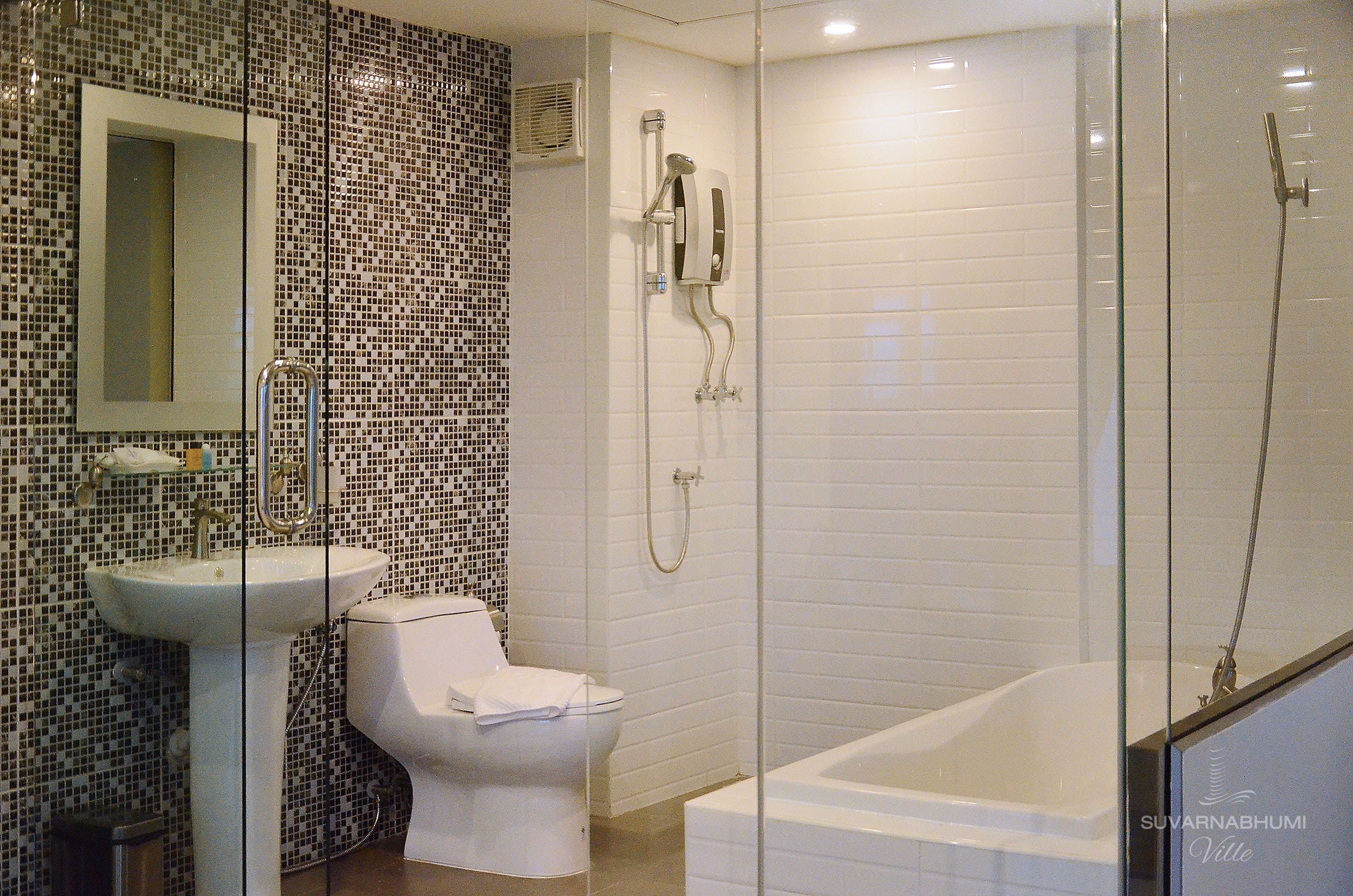 Un baño con lavamanos blanco, inodoro y zona de ducha con mampara de vidrio.
