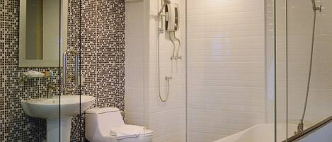 Un baño con lavamanos blanco, inodoro y zona de ducha con mampara de vidrio.