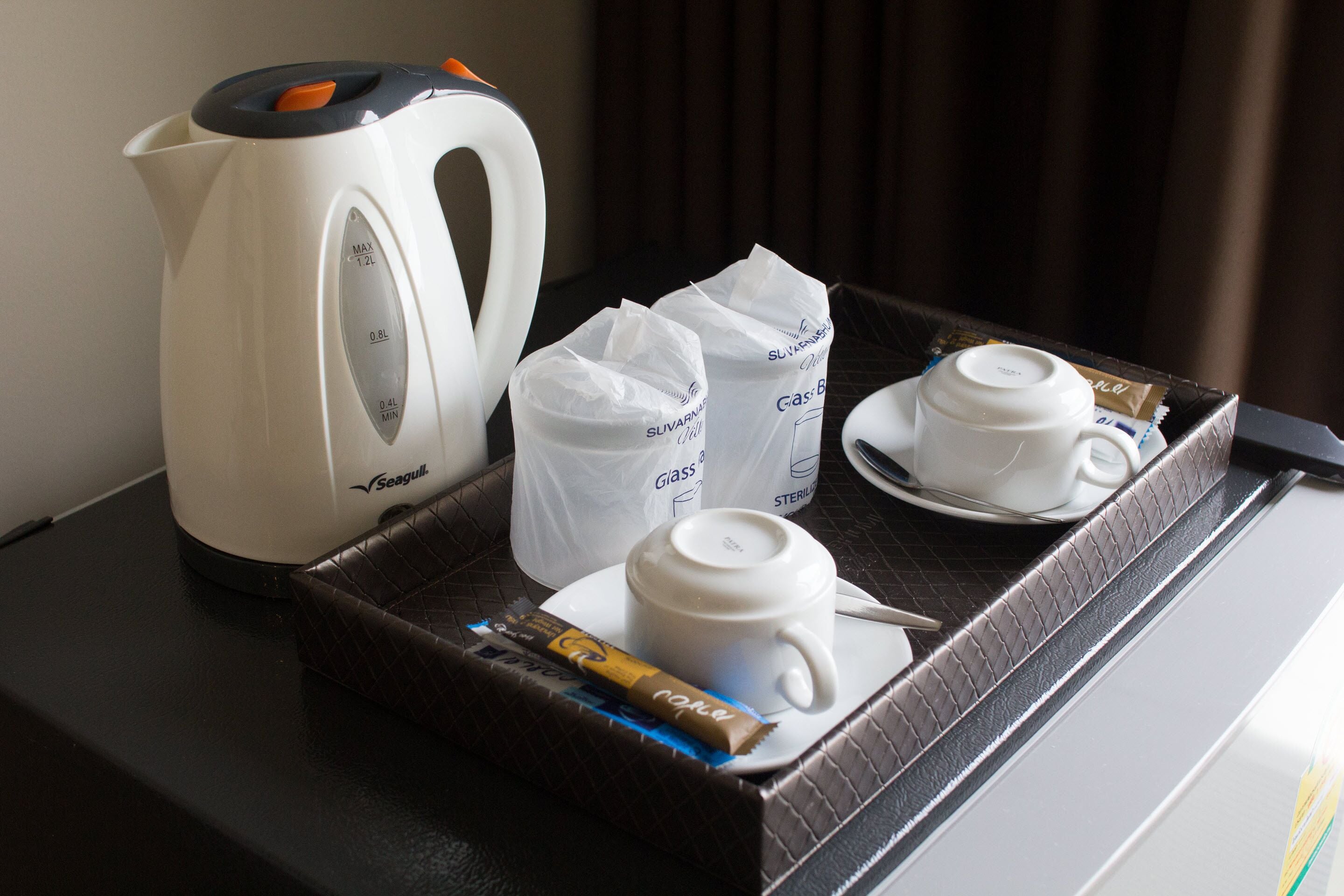 A tray with a Seagull kettle, two glass tumblers, and a chocolate bar.