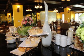 A buffet setup with various food items and a pitcher of water. - Suvarnabhumi Ville Airport Hotel (Bang Phli)