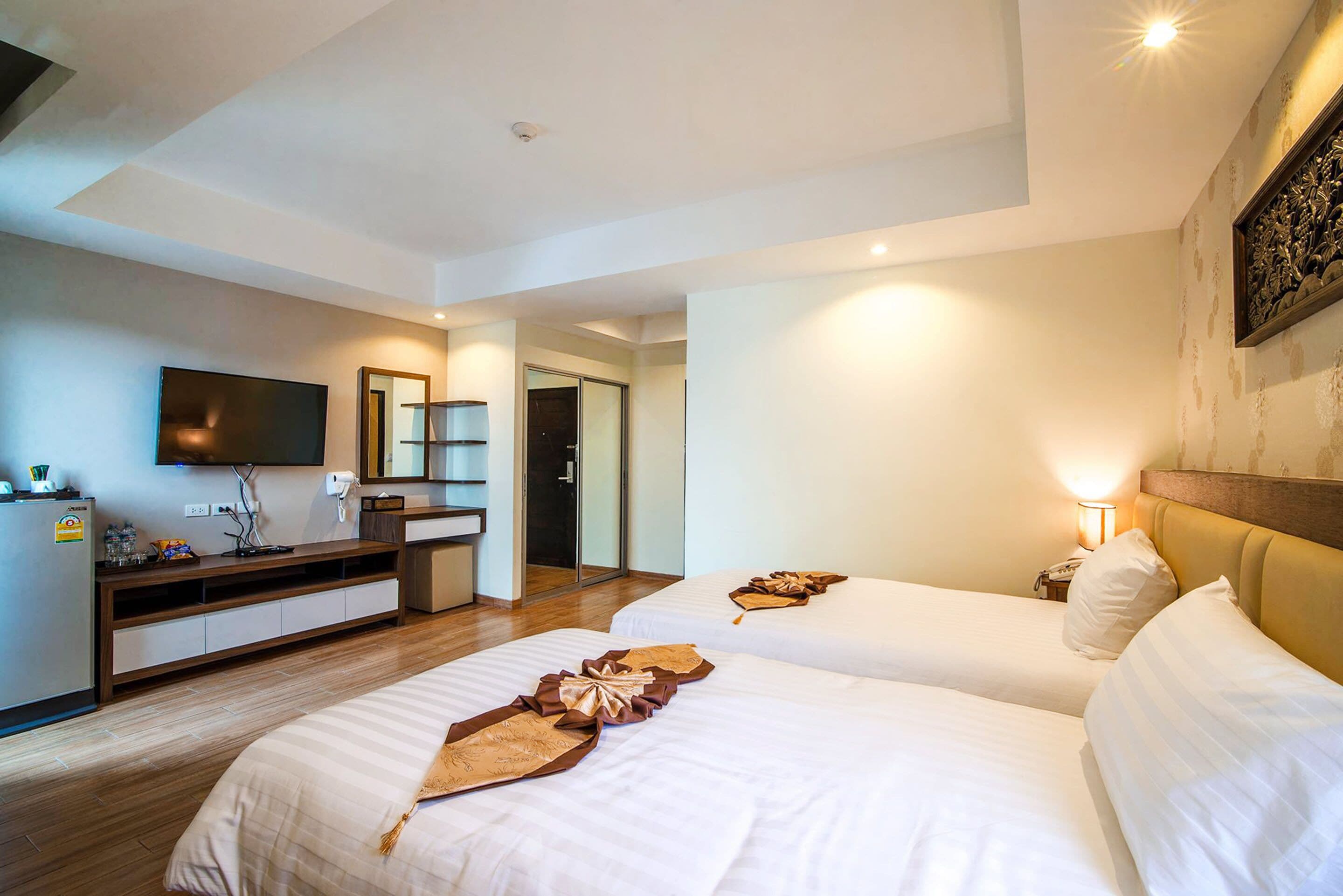A hotel room with two beds, a TV, a desk, and a bathroom.