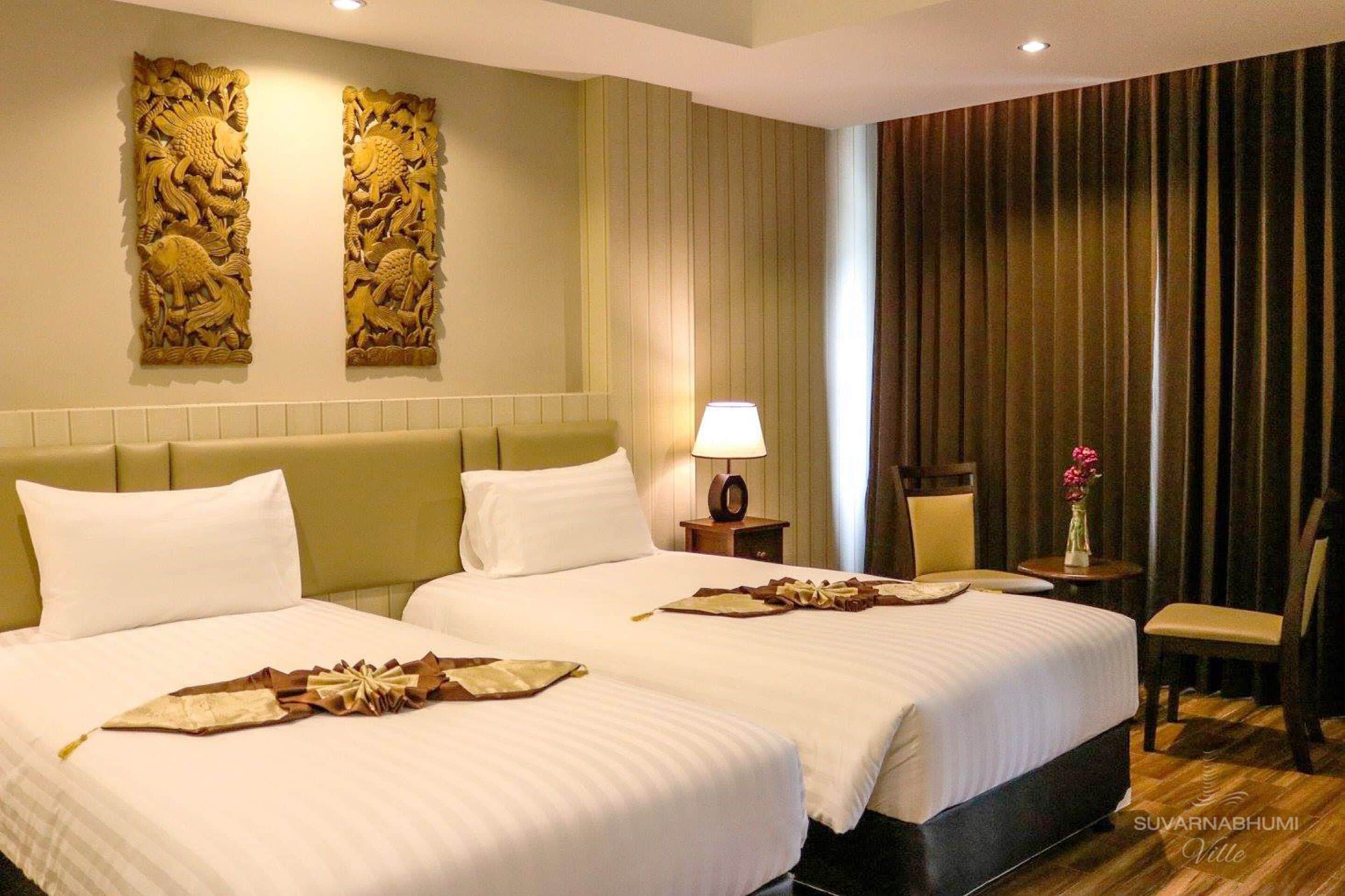 Une chambre d’hôtel avec deux lits, une table de chevet avec une lampe, une chaise et un panneau décoratif au mur.