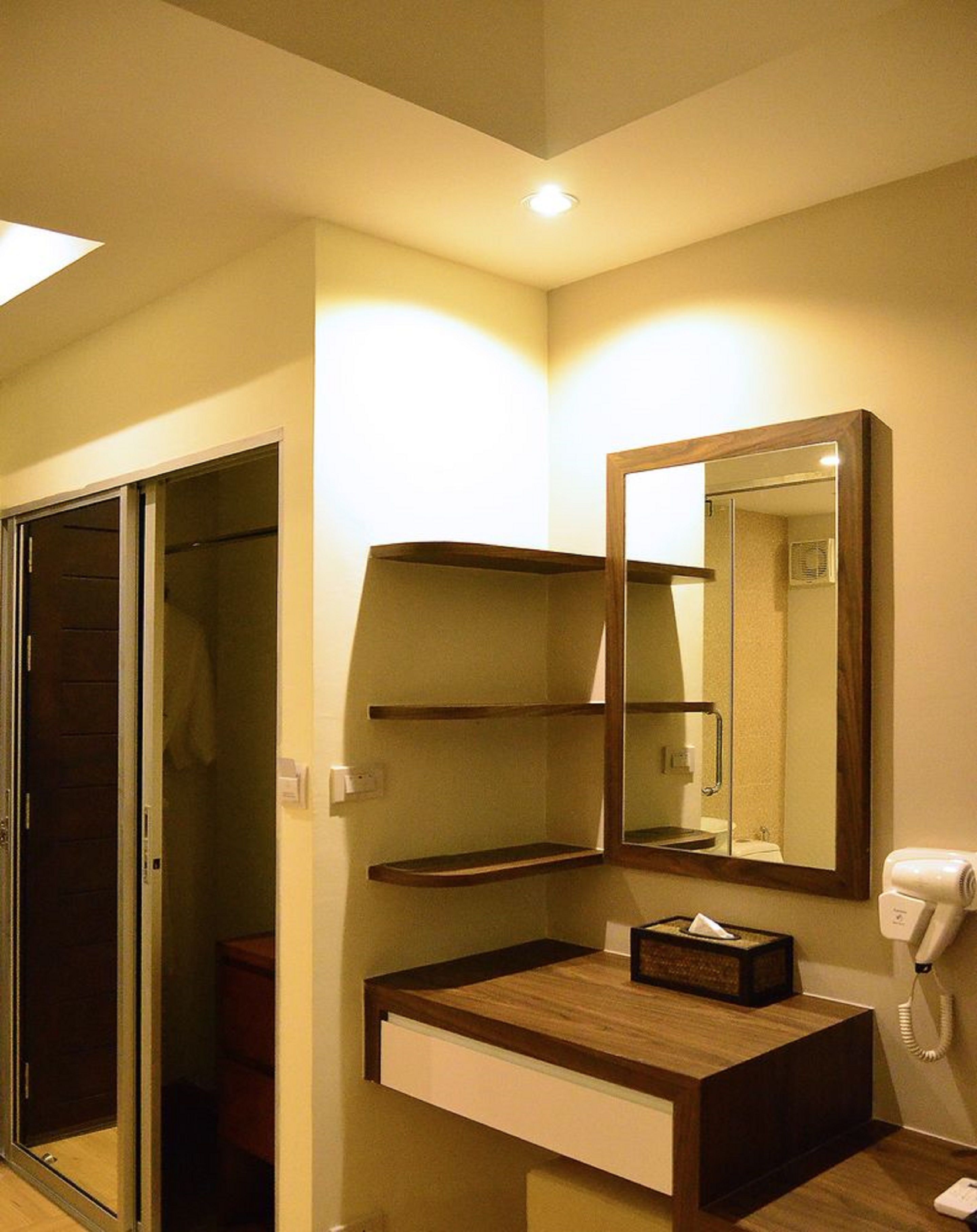 A modern bathroom with a wooden vanity, a mirror, a hairdryer, and a towel rack.