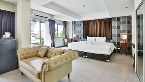 Ein modernes Hotelzimmer mit einem großen Bett, einer Sitzecke, einem Schreibtisch und Blick ins Freie.