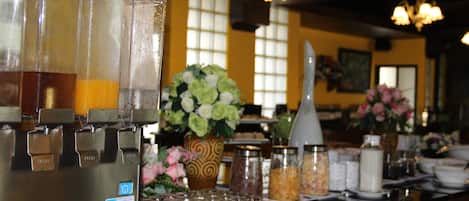 A bar area with a beverage dispenser, glassware, and various condiments.
