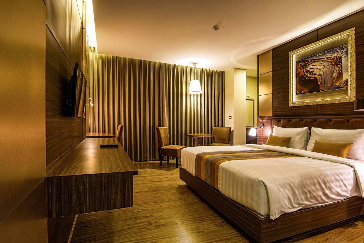 Habitación de hotel con una cama grande, un escritorio, una silla, una mesa y un cuadro en la pared.