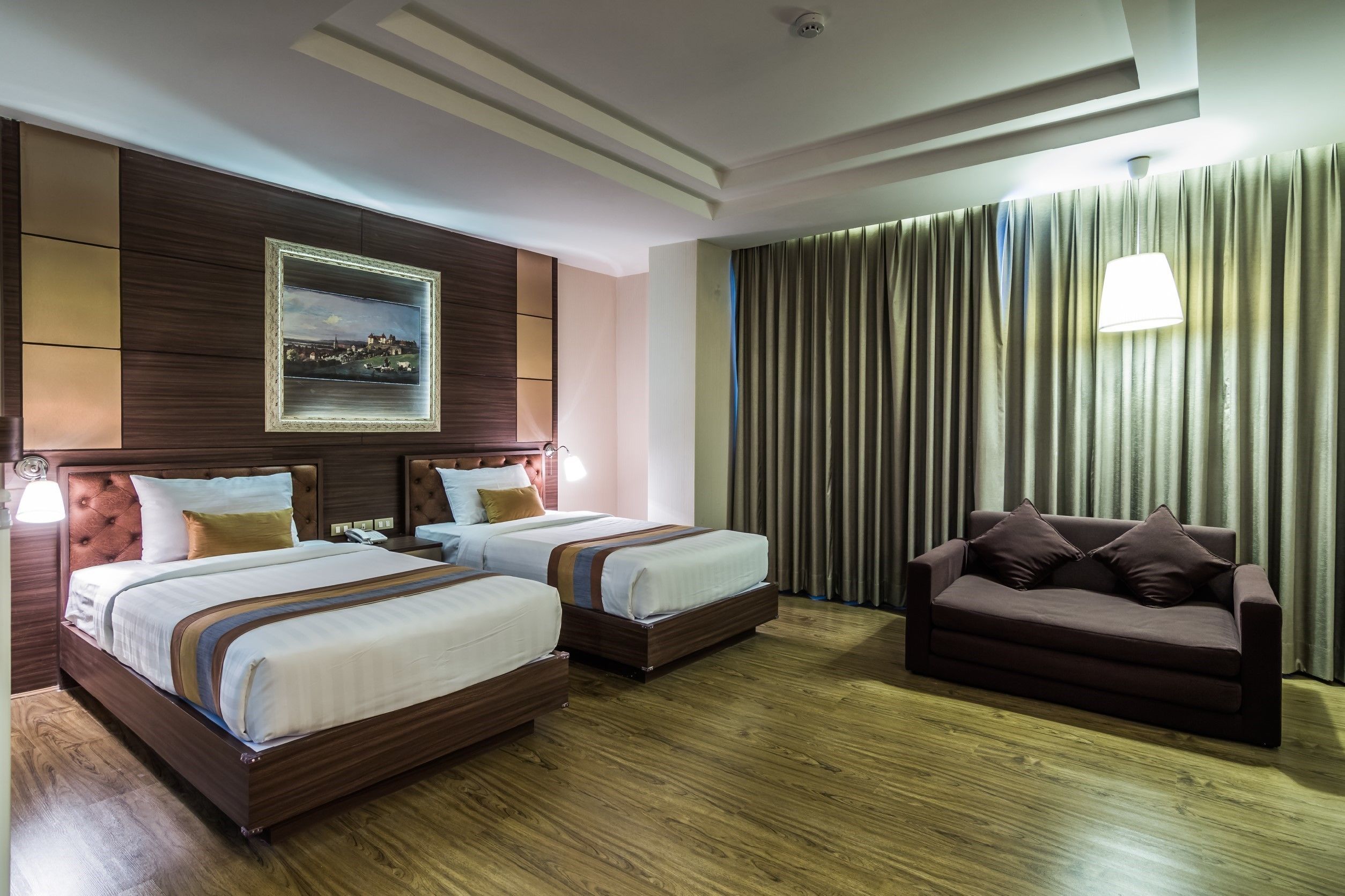 Una habitación de hotel con dos camas, un sofá, un cuadro en la pared y una cortina.