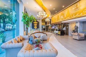 Eine geräumige Lobby mit gewölbter Decke, einem Empfangsbereich und einer Sitzecke mit Sofas und Sesseln.