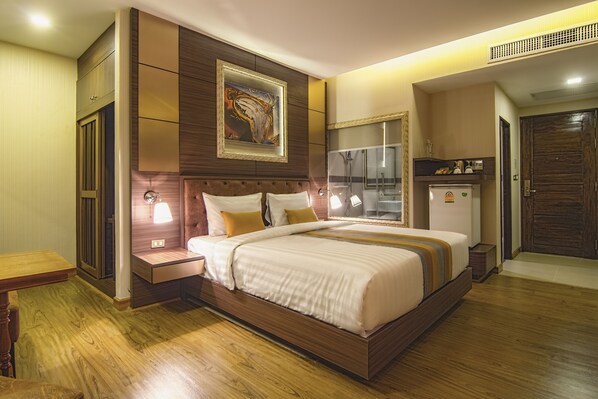 Un dormitorio moderno con una cama grande, mesitas de noche, un armario y un baño con espejo y lavabo.