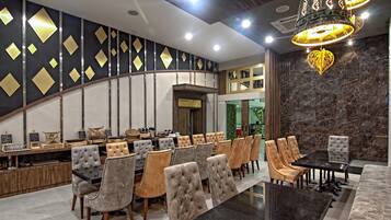 Un espace repas moderne avec un mur incurvé, une table au plateau noir et une variété de chaises rembourrées.