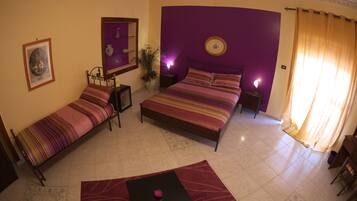 A bedroom with two single beds, a nightstand, a bedside table, a lamp, a mirror, and a window with curtains.