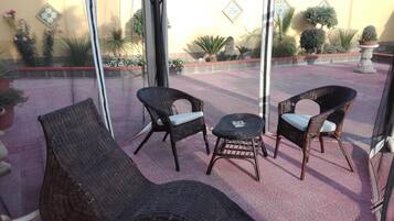 Un patio con mobiliario de mimbre, incluyendo dos sillones y una mesita, y un sofá.