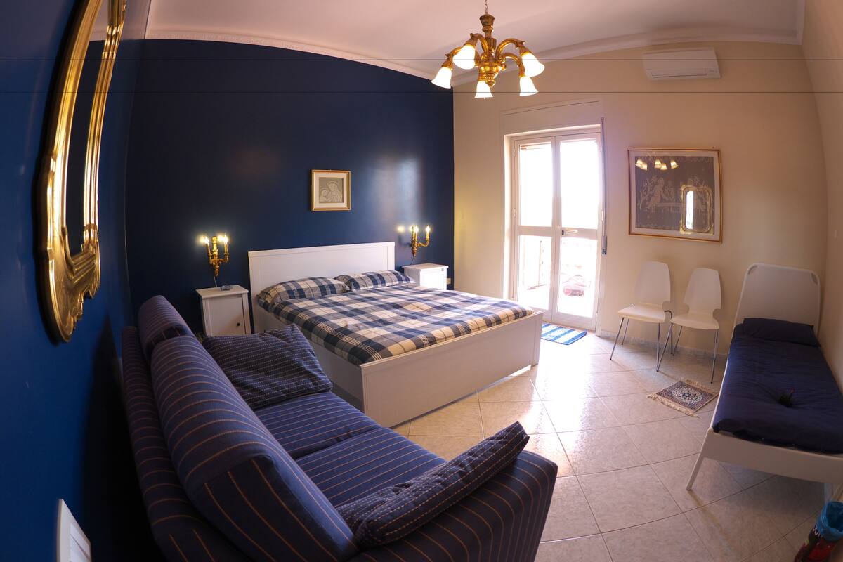 Un dormitorio con cama, sofá, sillón y mesita de noche.