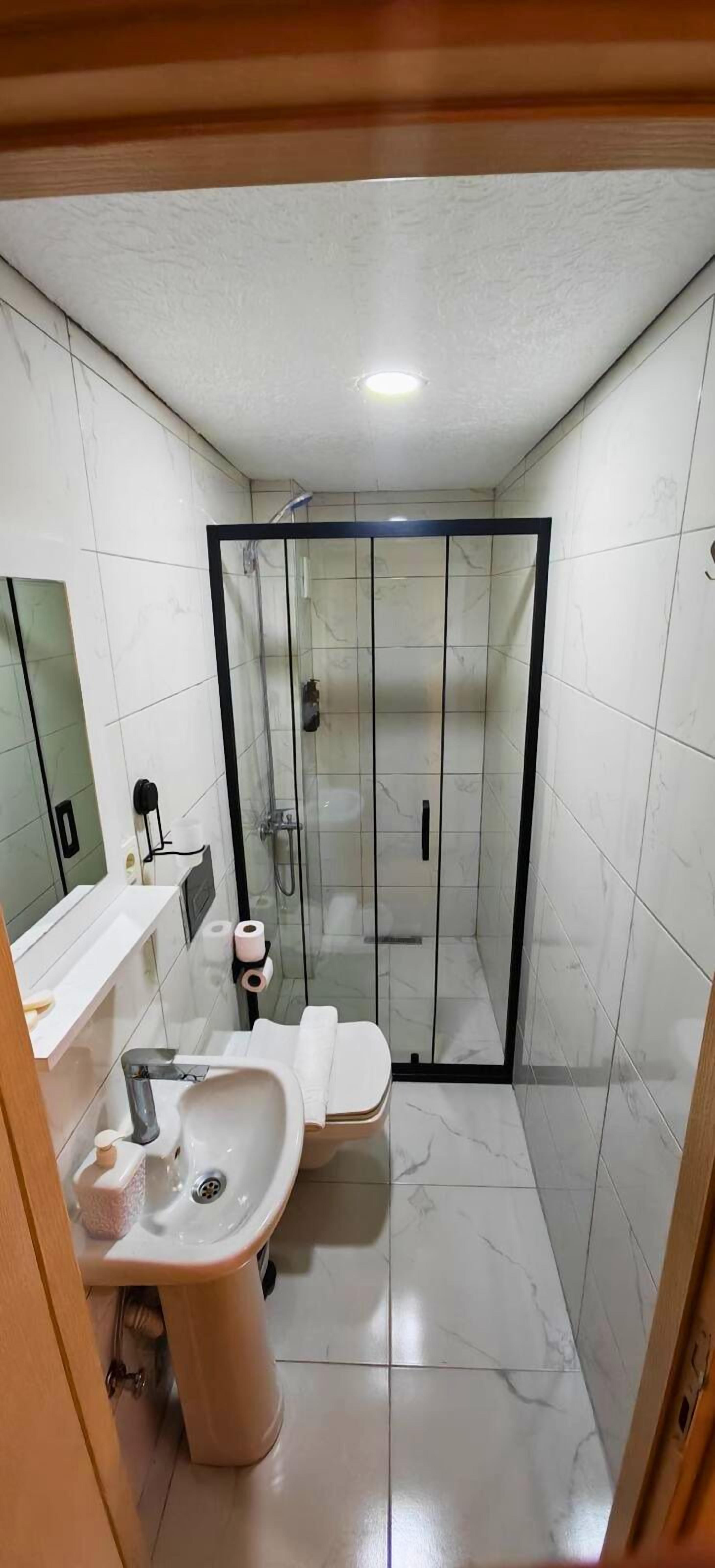 Un baño con ducha envuelta en vidrio, lavabo e inodoro.