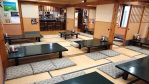 A traditional Japanese inn with tatami mat flooring, low tables, and cushions.