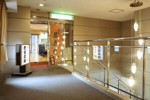Relax in our spacious lobby with a polished floor and glass railing, surrounded by pendant lights and a seating area with chairs and tables.