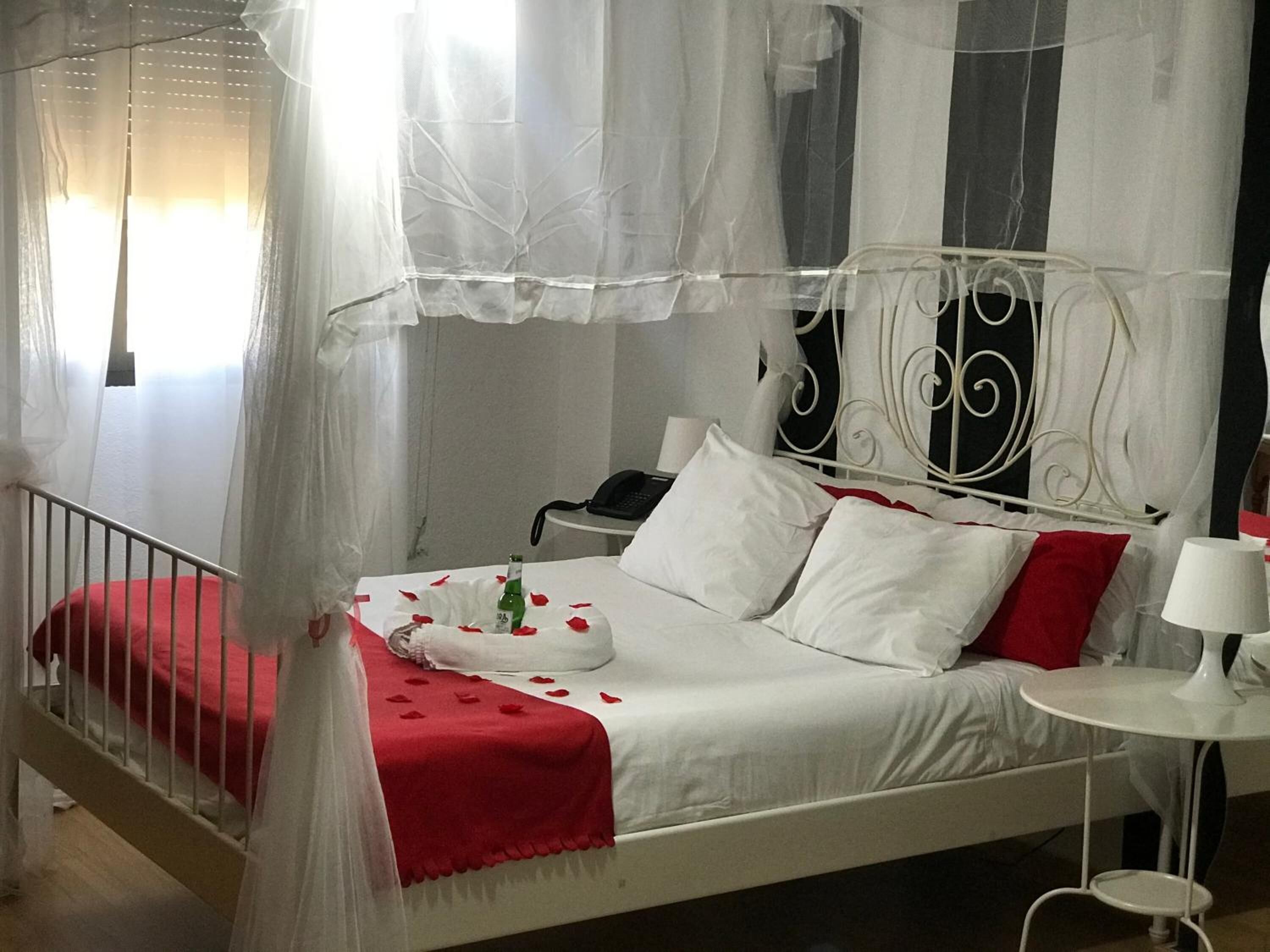 A bed with a canopy, a bedside table, a lamp, and a telephone.