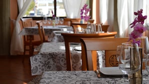 A restaurant with tables set for dining, featuring patterned tablecloths and wooden chairs. - Hotel Argos Murcia (Cehegin)