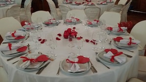 A round dining table set with white tablecloths, red napkins, and clear glassware. - Hotel Argos Murcia (Cehegin)