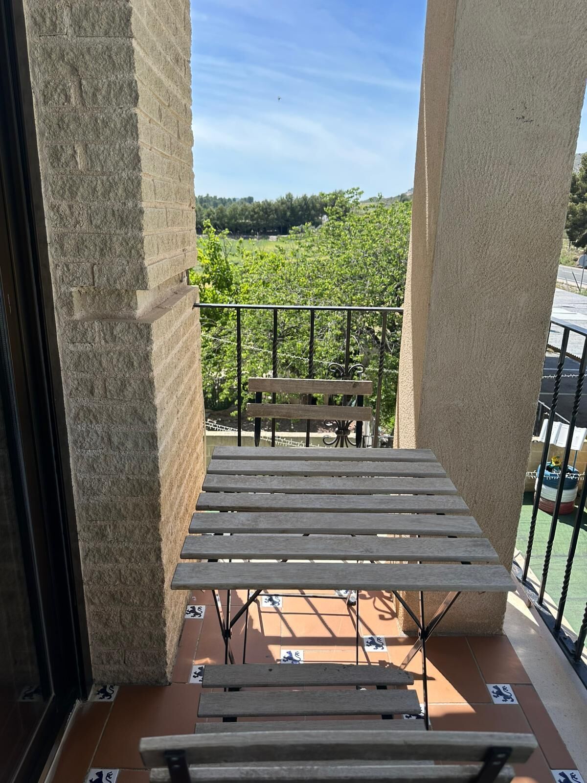 Ein Balkon mit einer Holzbank und einem Tisch, mit Blick auf eine grüne Landschaft.