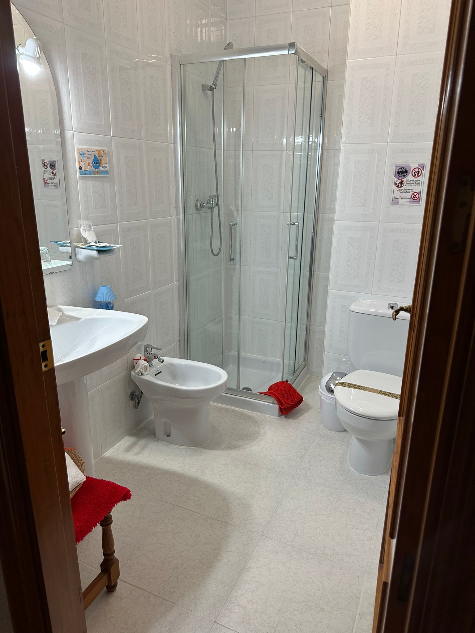 A bathroom with a glass-enclosed shower, a sink, a bidet, and a toilet.