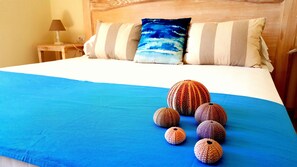 A bed with a blue bedspread, a wooden headboard, and a pillow with a blue ocean design. - Brezza Marina Luxury Rooms (Cagliari)