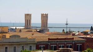 A coastal cityscape with historic buildings and two prominent towers.