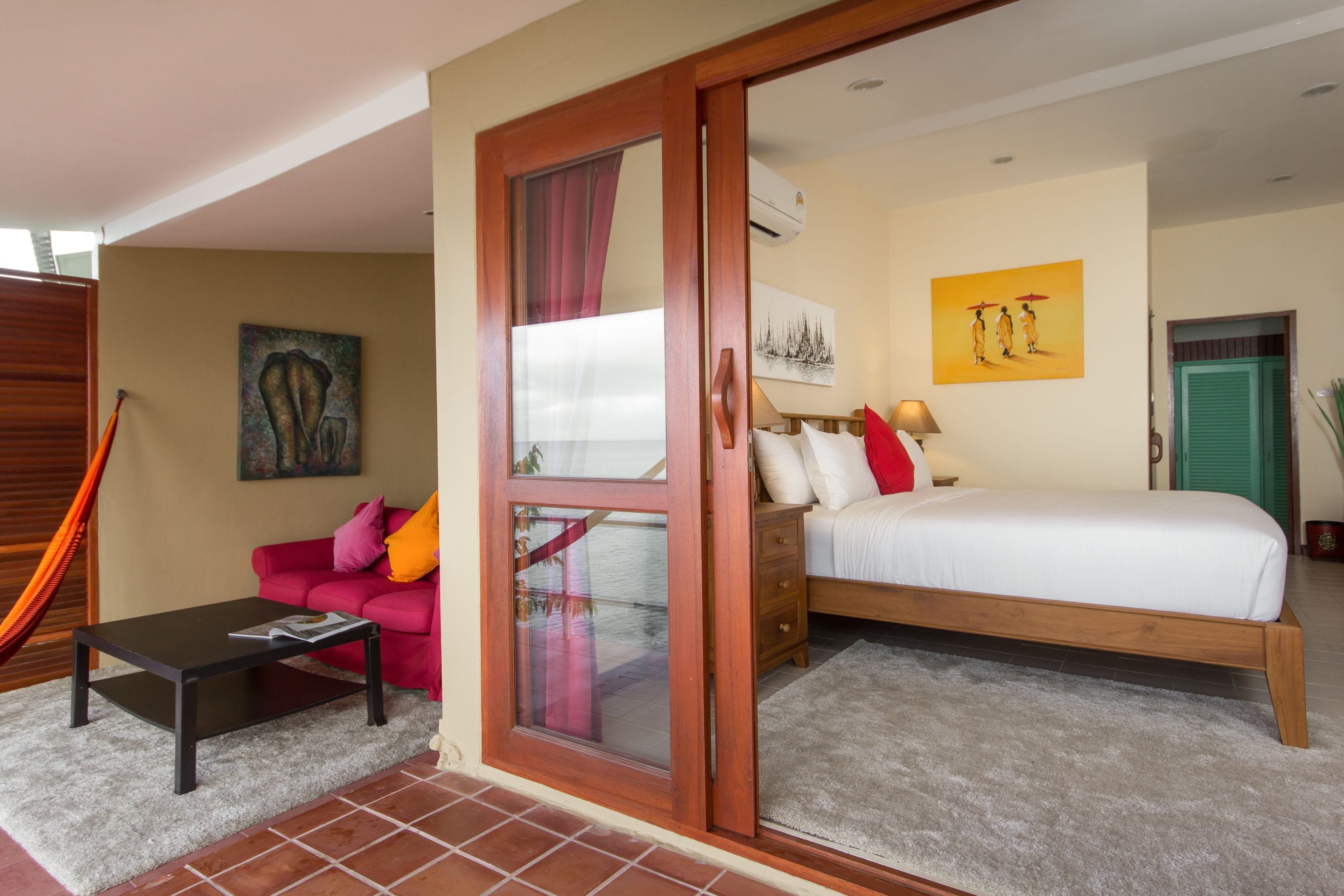 Quarto com cama, mesa de cabeceira, luminária, sofá e janela com cortinas.