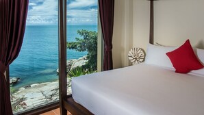 A bedroom with a large window overlooking a rocky coastline and the sea. - Boujis Boutique Resort (Koh Samui)