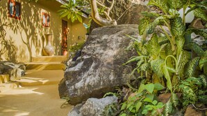 A stone pathway leading to a building with a large rock in the foreground and lush greenery around. - Boujis Boutique Resort (Koh Samui)