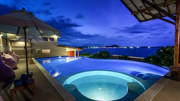 Een buitenzwembad, parasols bij het zwembad en ligstoelen