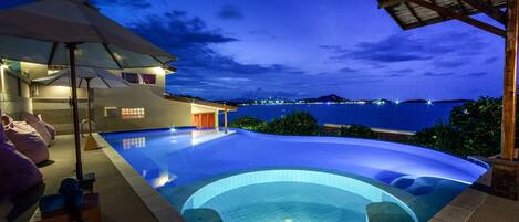 Alberca al aire libre, sombrillas en la alberca y camastros