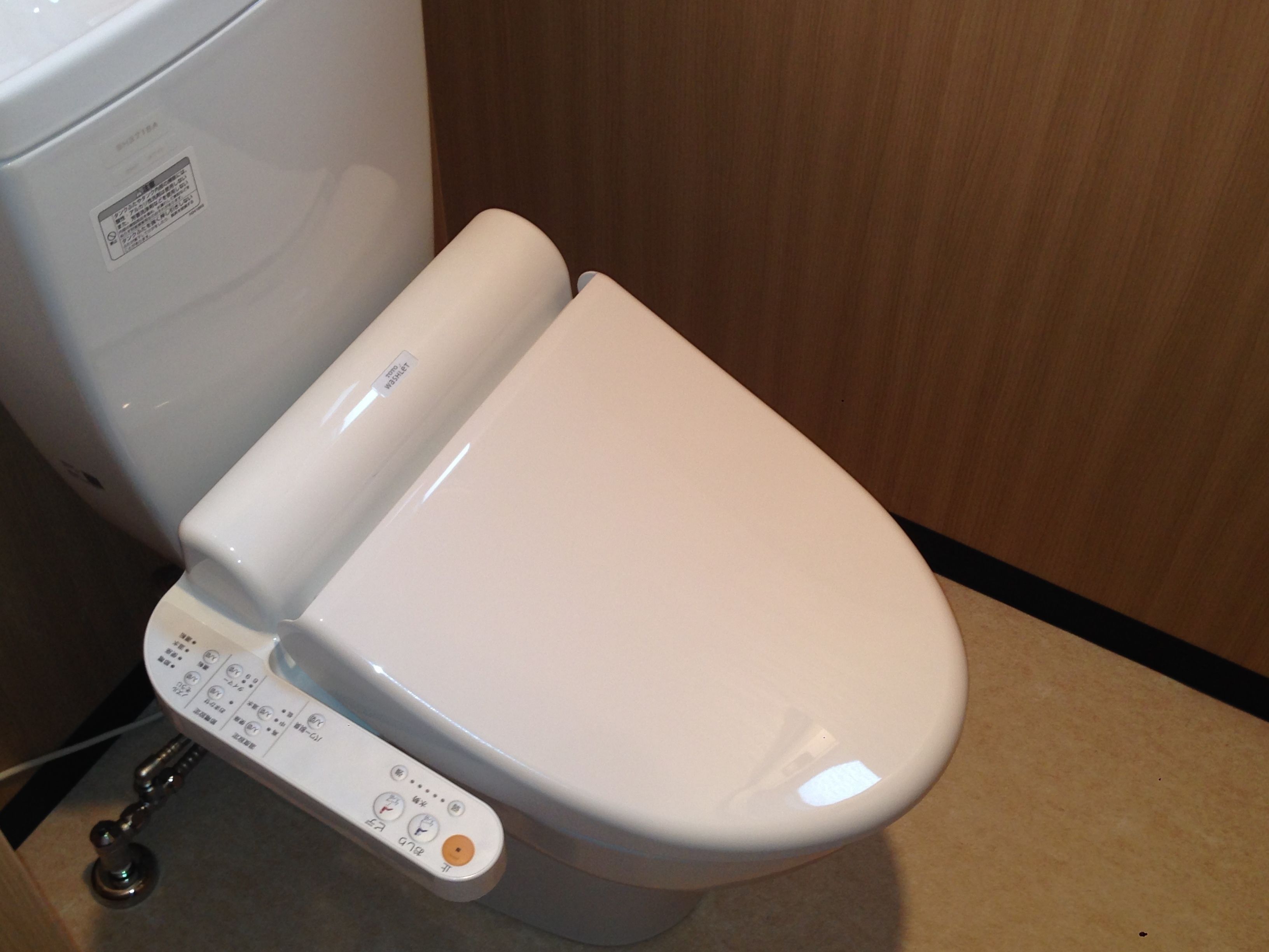 A modern toilet with a control panel and a bidet attachment.