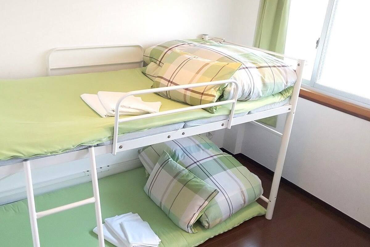 Ein Etagenbett mit grüner Bettwäsche und karierten Kissen.