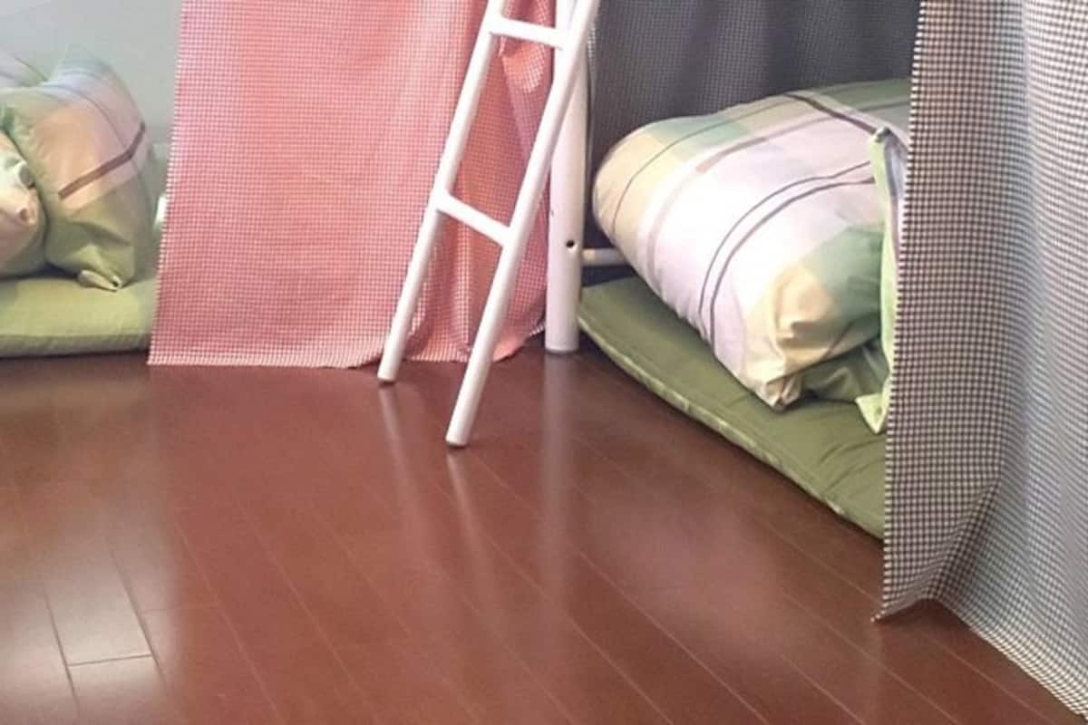 Ein Zimmer mit zwei Betten, einer Leiter und einem Vorhang.