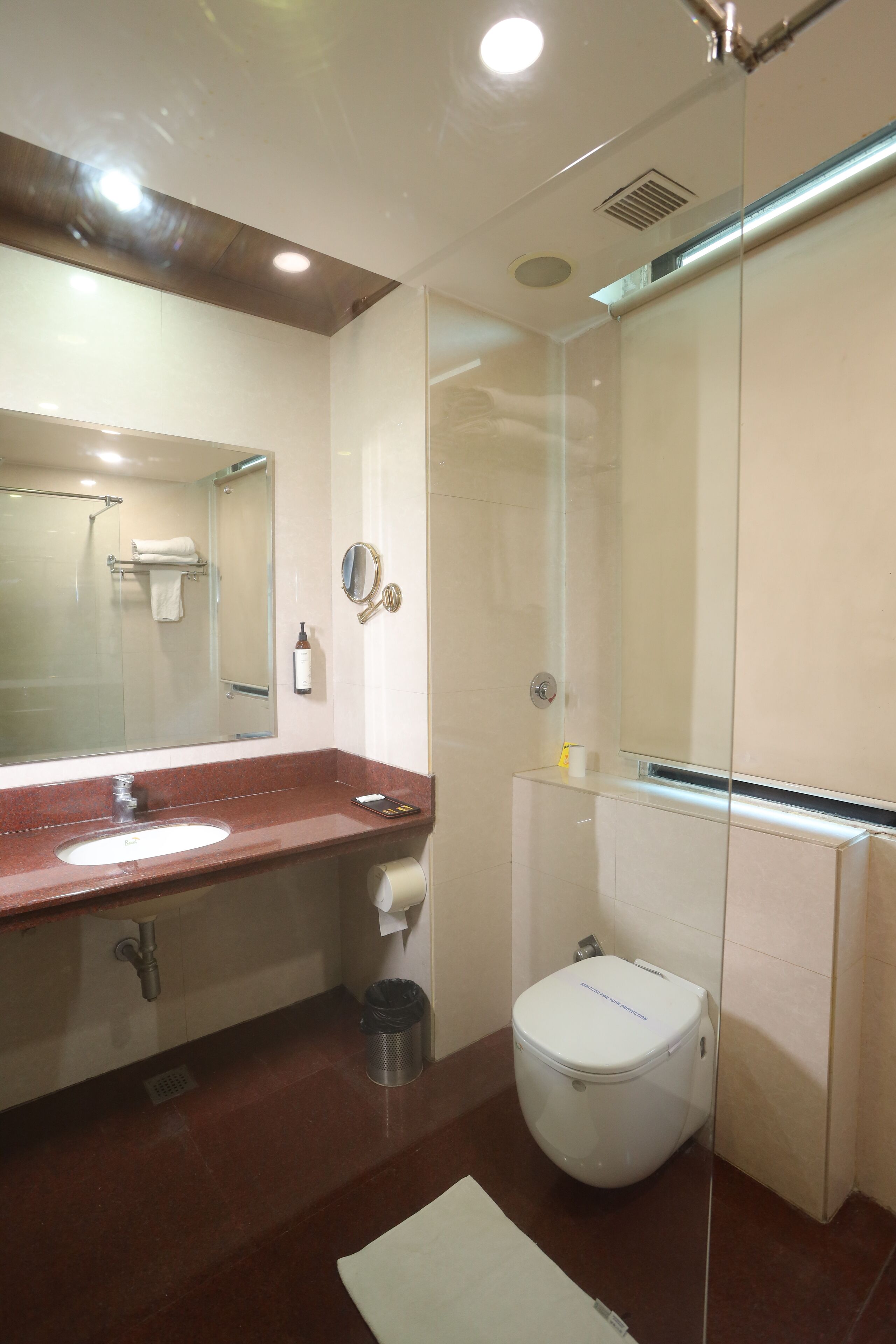 Un bagno moderno con lavabo in marmo, uno specchio grande, un water e una cabina doccia in vetro.