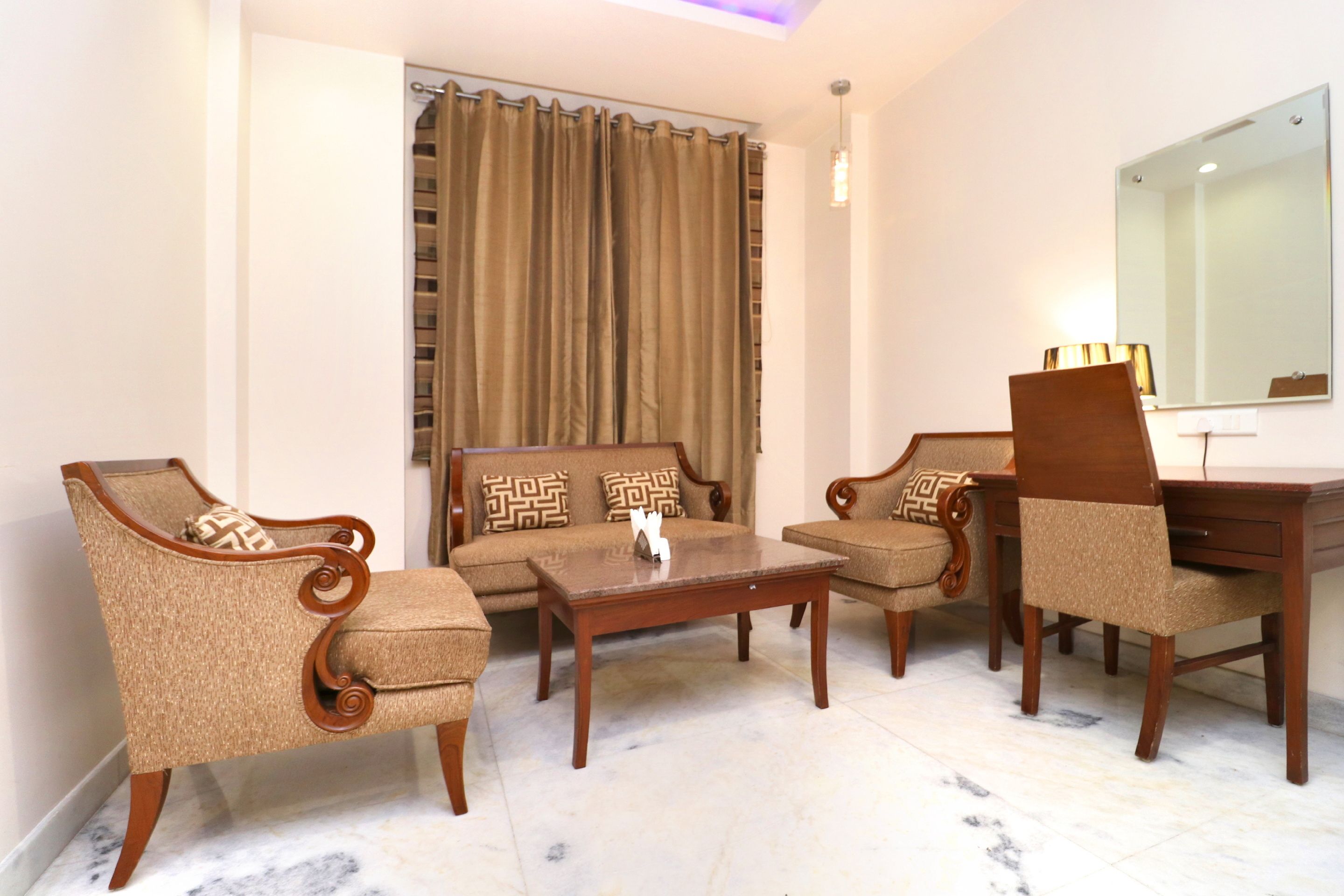 A living room with a sofa, two armchairs, a coffee table, and a desk with a lamp.