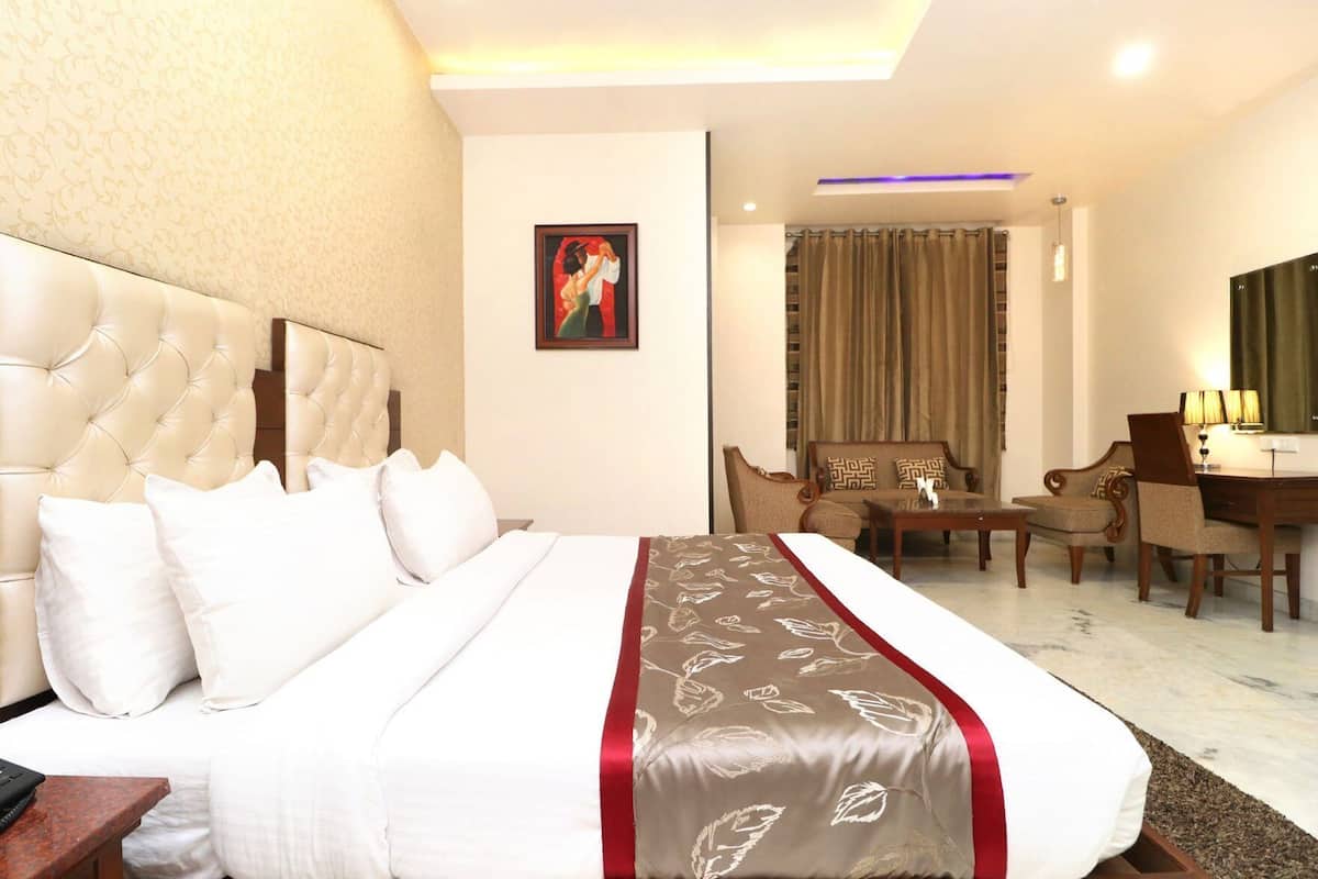 A hotel room with a large bed, a desk, a chair, and a sofa.