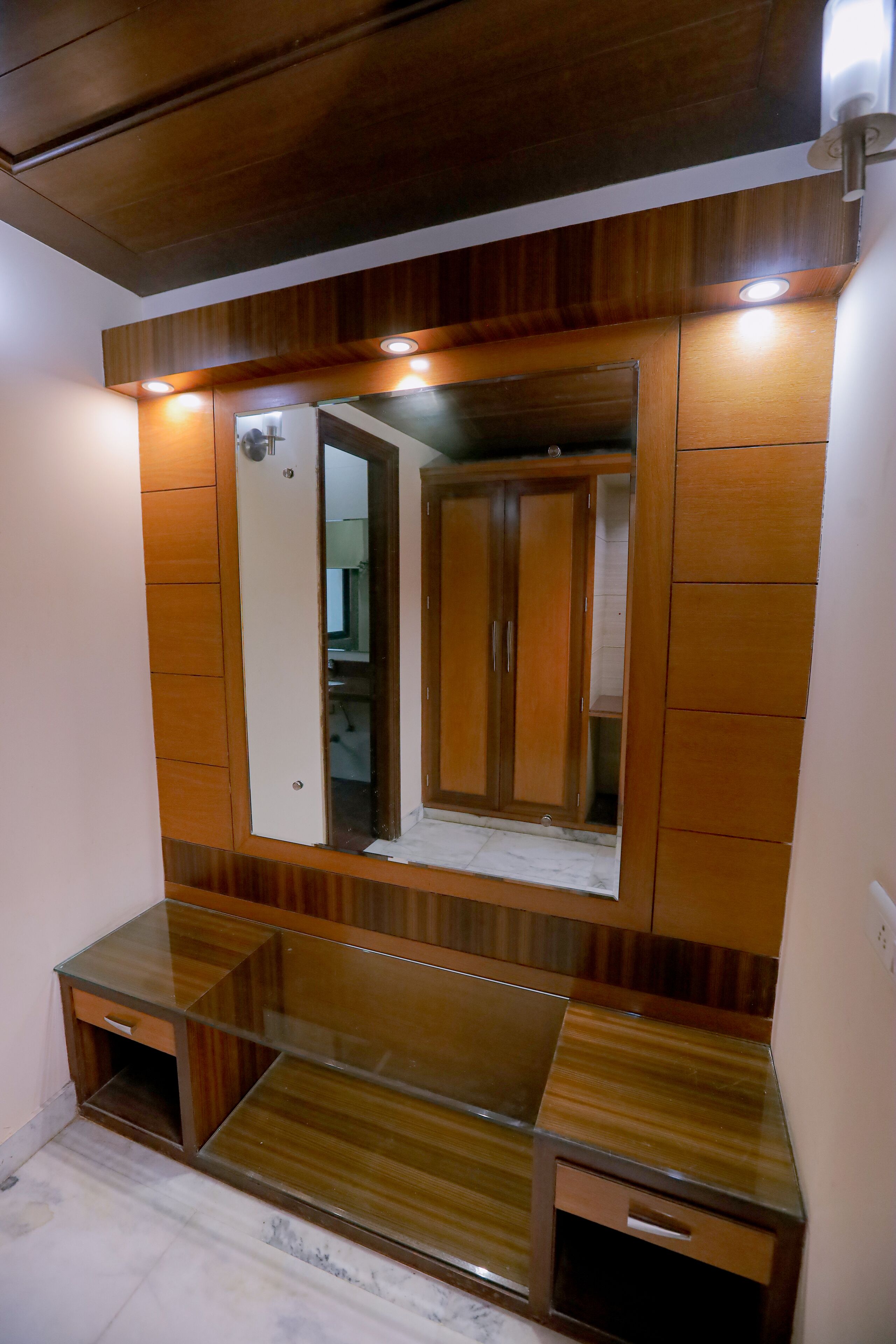 A bathroom with wooden cabinetry, a large mirror, and a glass shower enclosure.