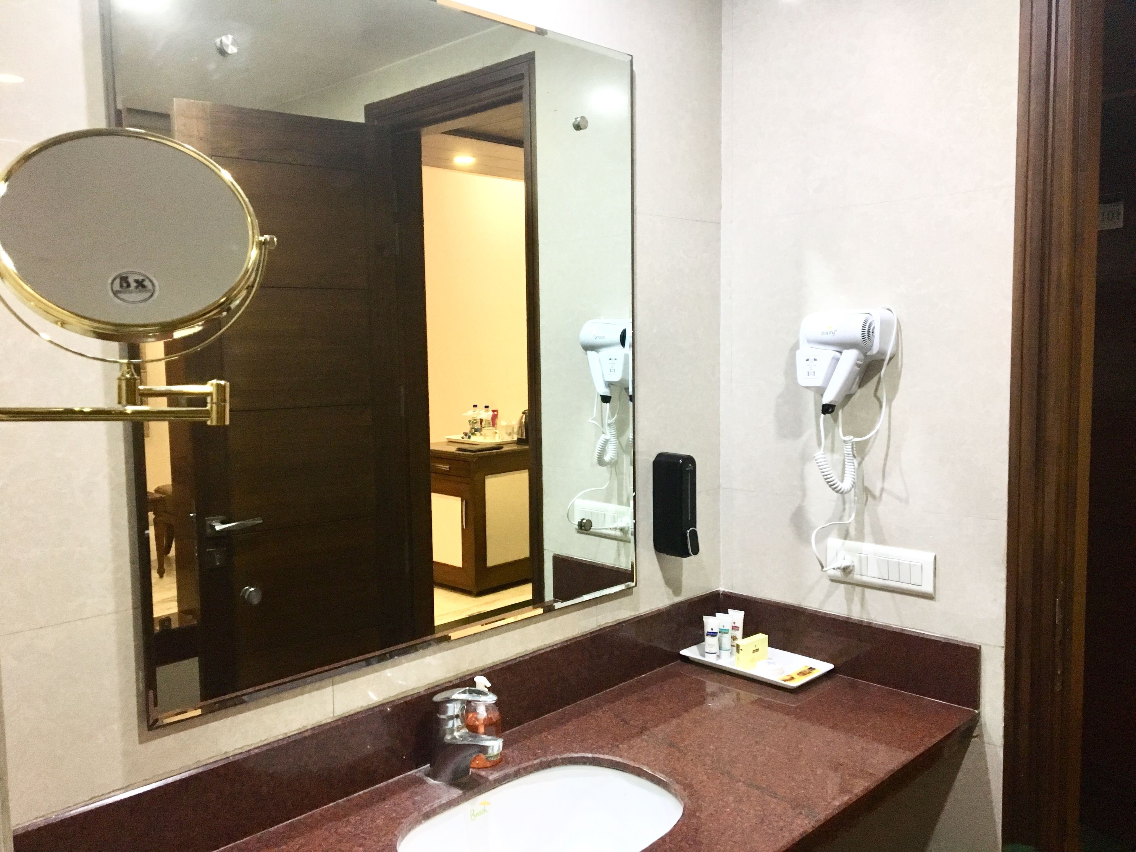 A bathroom with a mirror, sink, hairdryer, and a phone.