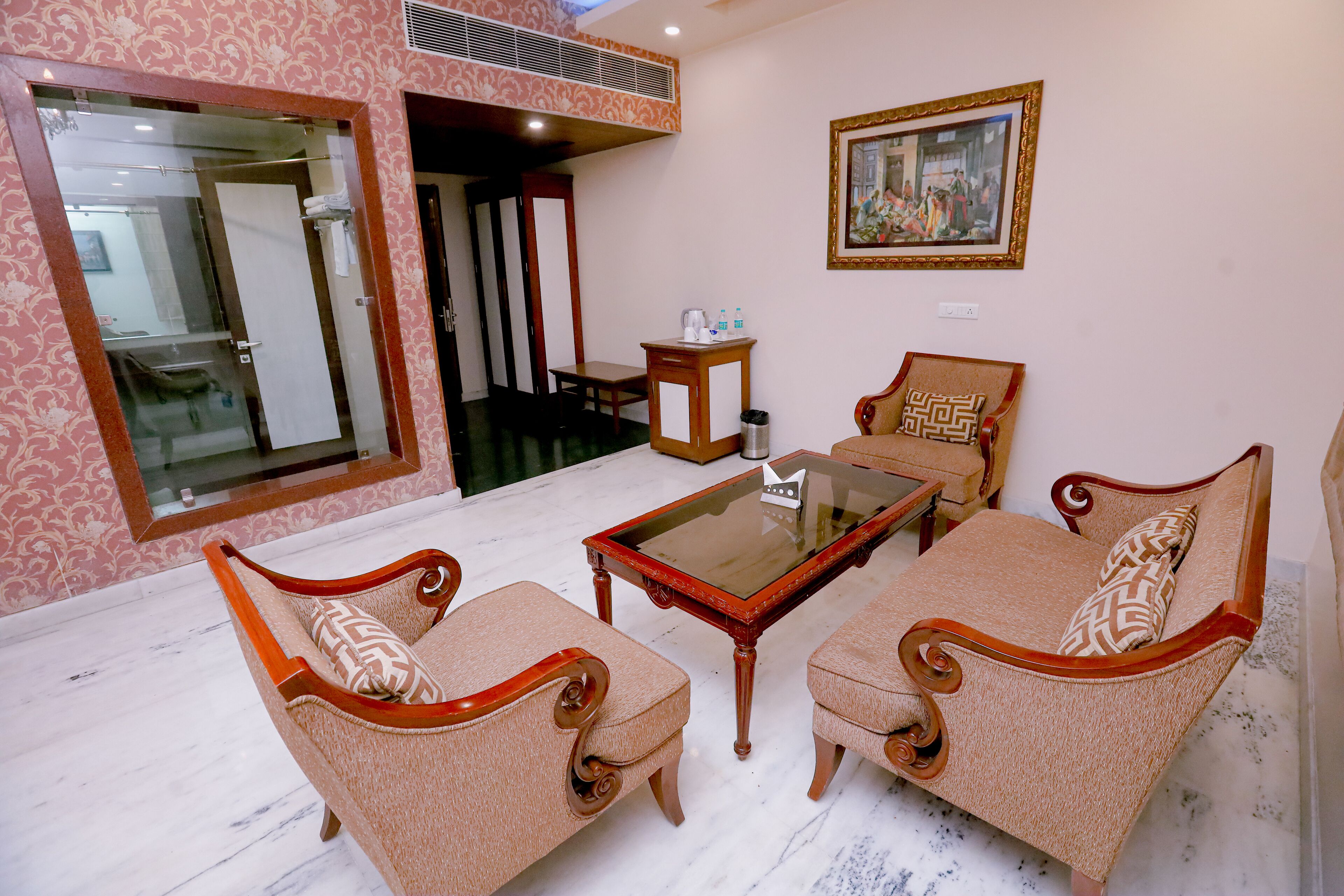 A room with a glass partition, a wooden table, two sofas, a small wooden side table, and a framed picture on the wall.