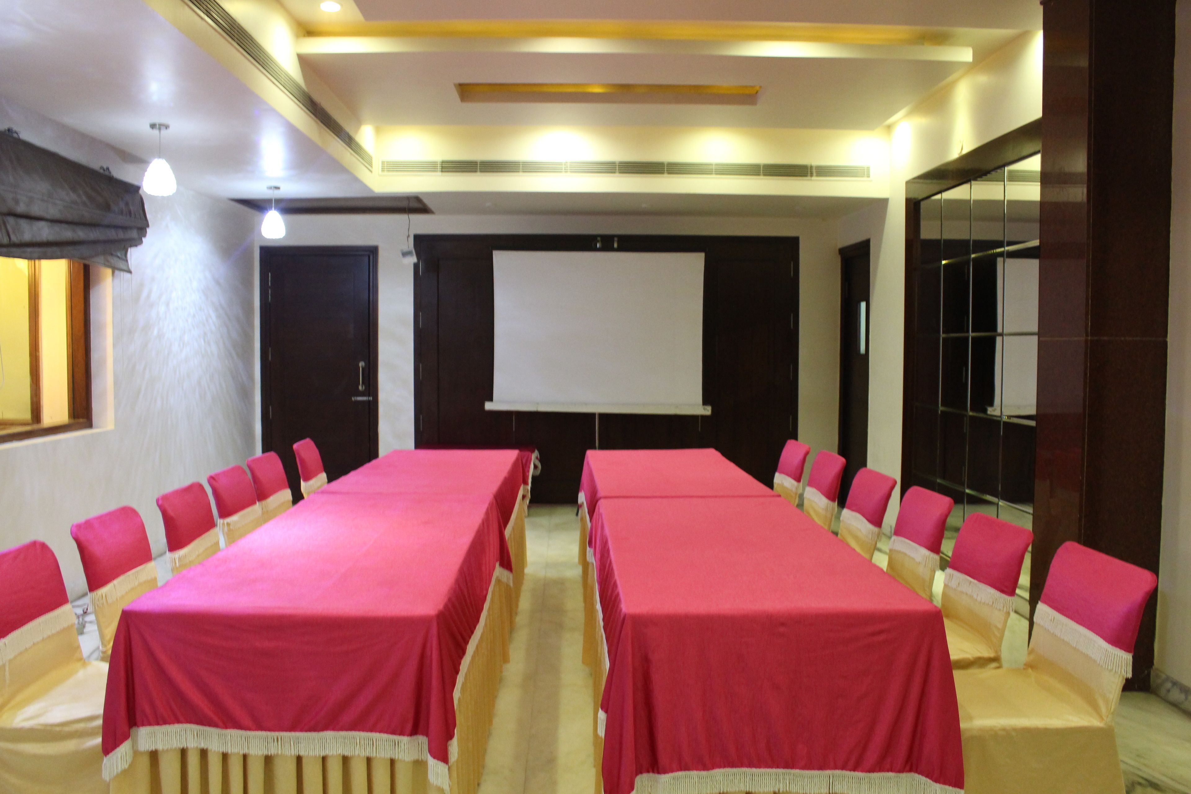 A conference room with long tables and chairs, a projector screen, and a large window.