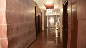 A corridor with marble walls, a chandelier, and a reception area with a vase of flowers.