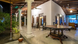A spacious indoor area with a high ceiling, wooden beams, and a large table with chairs. - Green Villa (Unawatuna)
