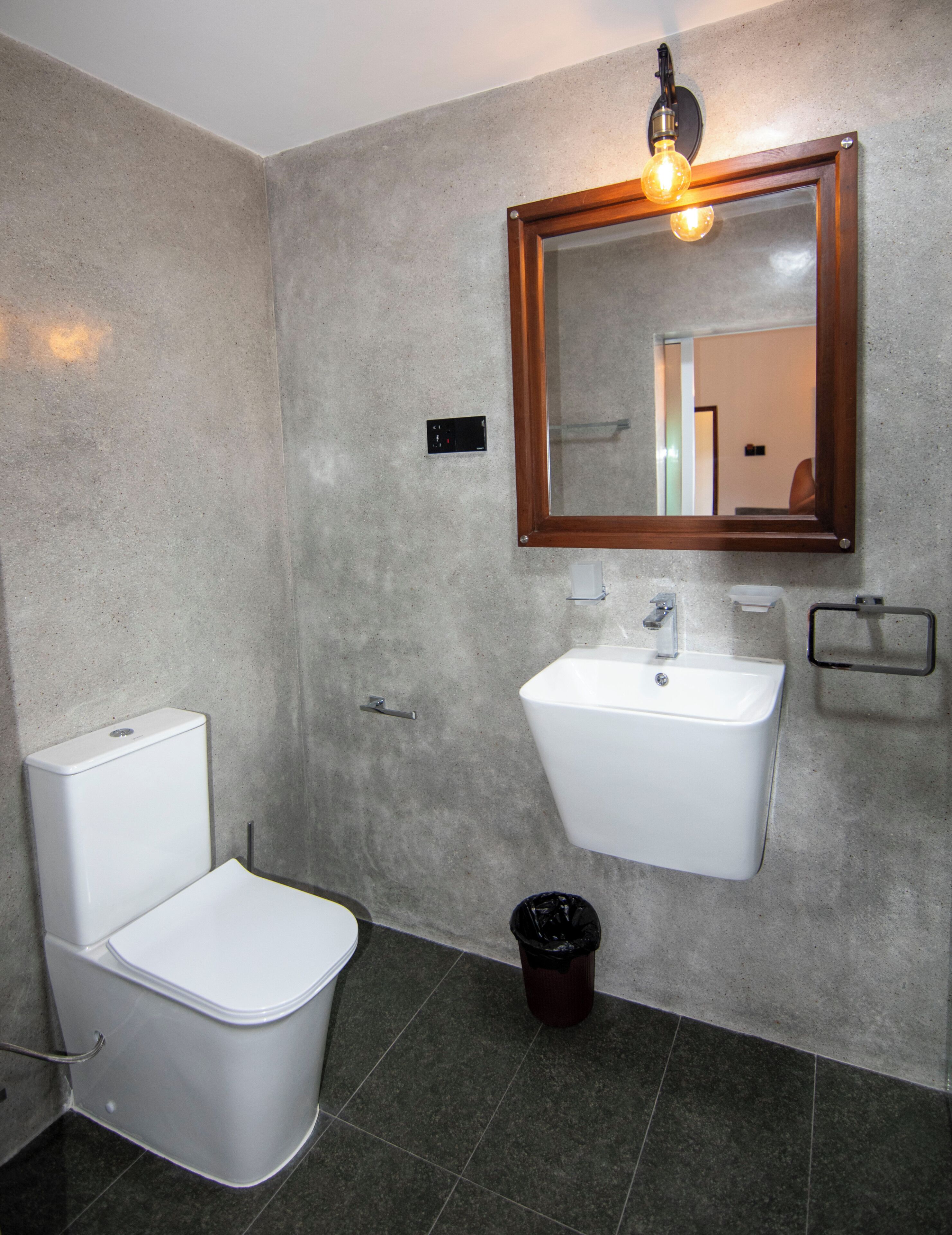 A bathroom with a toilet, sink, and mirror.