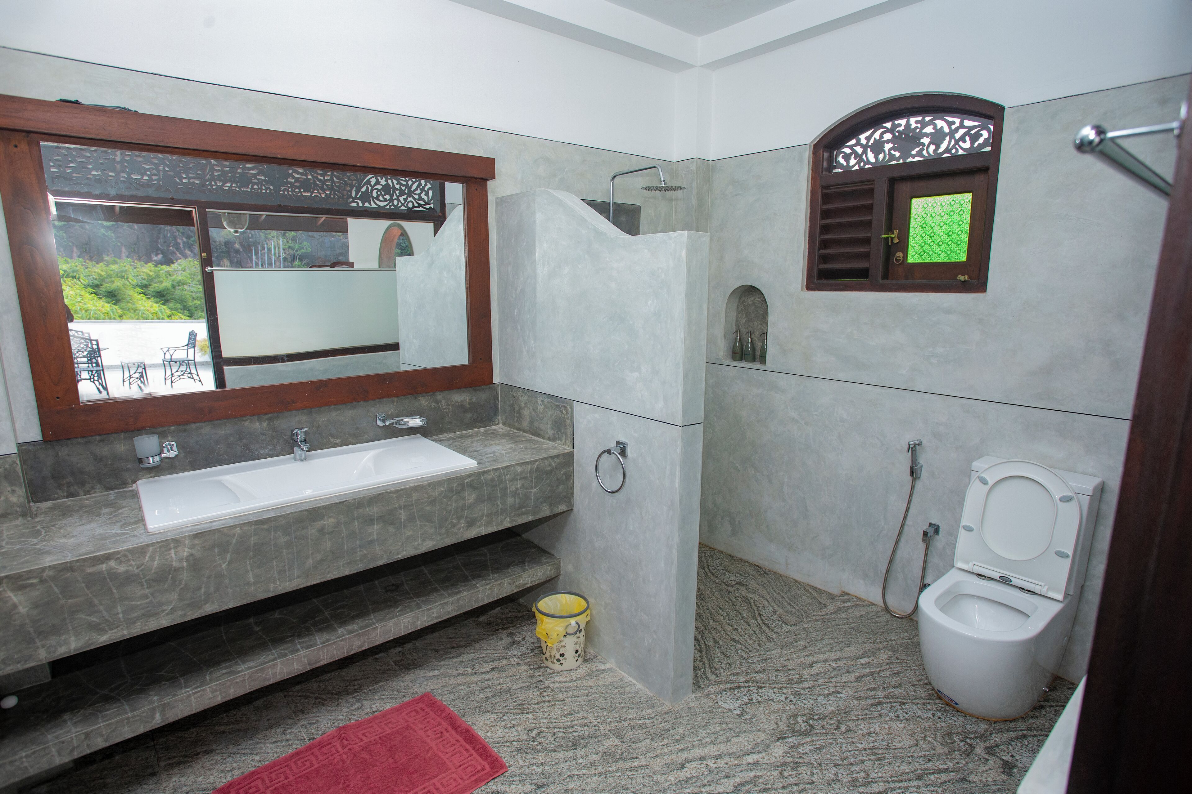 A bathroom with a sink, mirror, toilet, and shower.