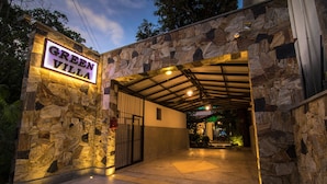 A stone-walled entrance to Green Villa with a metal gate and a covered walkway. - Green Villa (Unawatuna)