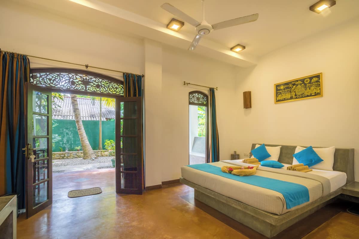 A bedroom with a bed, a ceiling fan, and a view of the outdoors.