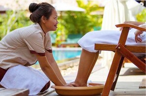 A person sitting on a wooden chair by a poolside, with a towel on the ground. - Holy Angkor Hotel (Siem Reap)